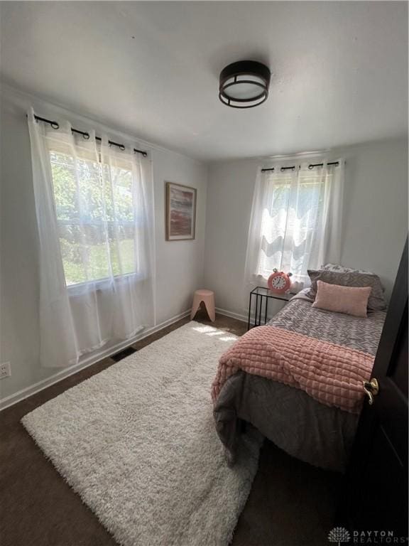carpeted bedroom with multiple windows and baseboards