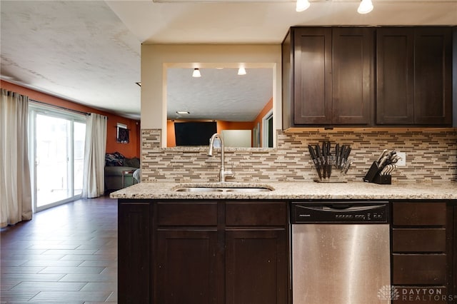 kitchen with dishwasher, a sink, decorative backsplash, dark brown cabinetry, and light stone countertops