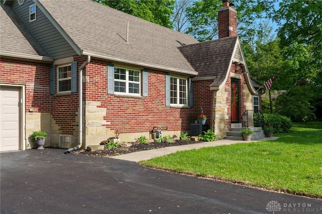 2182 La Grange Rd, Beavercreek, OH 45431 - view of home's exterior featuring a shingled roof, a chimney, brick siding, a lawn, and driveway