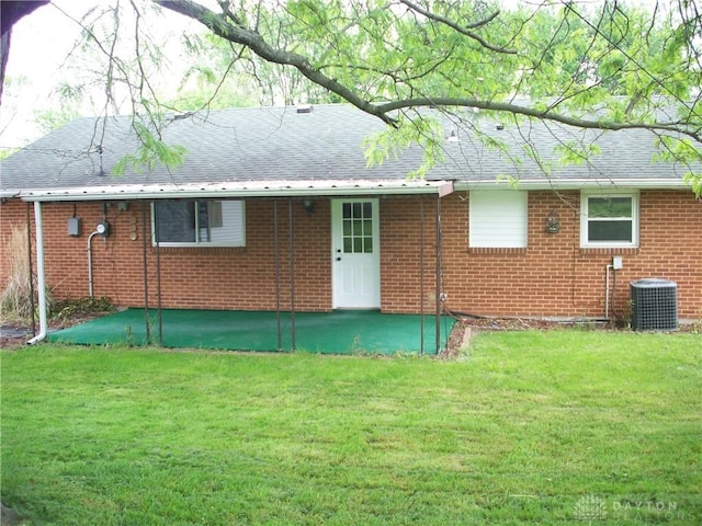 back of property with brick siding, a lawn, and central air condition unit