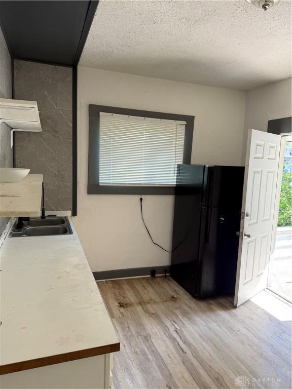90 S Sperling Ave Unit 88, Dayton, OH 45403 - kitchen with freestanding refrigerator, a sink, light wood-style floors, light countertops, and a textured ceiling