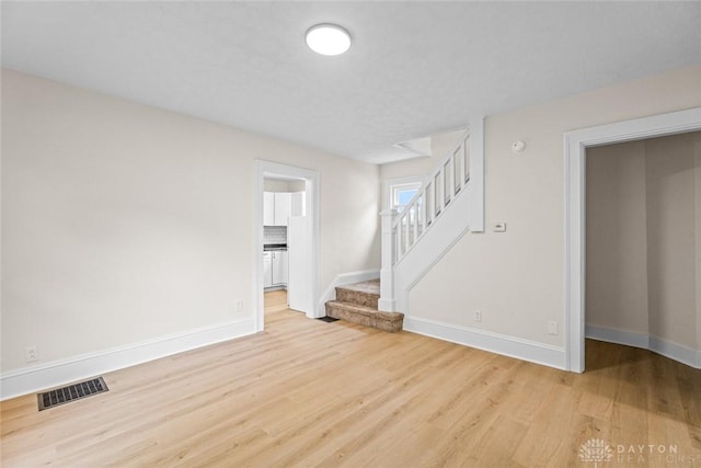1235 W Jefferson St, Springfield, OH 45506 - unfurnished living room featuring wood finished floors, baseboards, and stairway