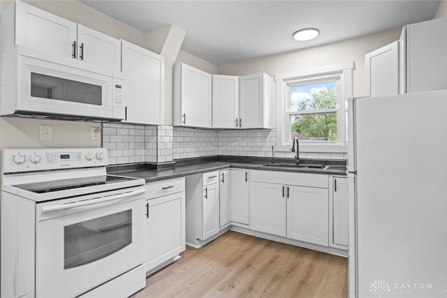 1235 W Jefferson St, Springfield, OH 45506 - kitchen featuring white appliances, a sink, light wood-style flooring, dark countertops, and white cabinetry
