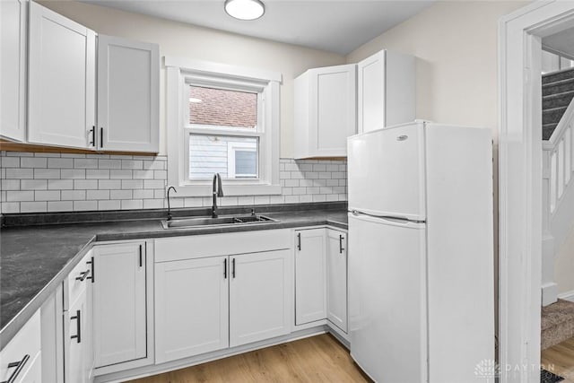 1235 W Jefferson St, Springfield, OH 45506 - kitchen with freestanding refrigerator, a sink, dark countertops, light wood-type flooring, and decorative backsplash