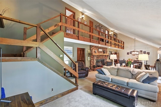 living area with lofted ceiling, carpet flooring, stairs, a brick fireplace, and a chandelier