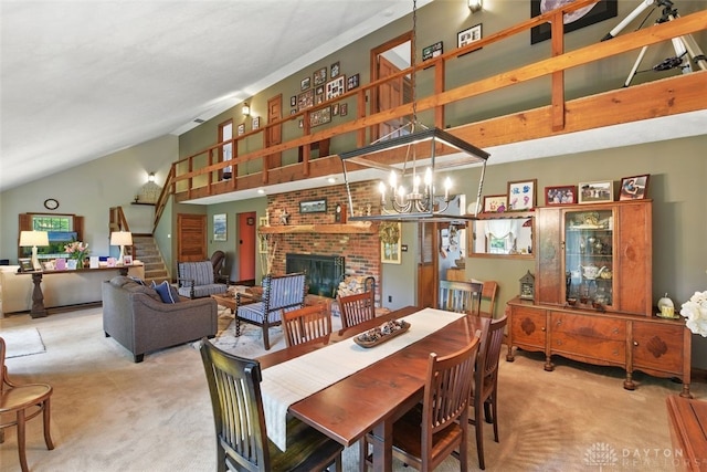 dining area featuring carpet, stairs, high vaulted ceiling, a brick fireplace, and a chandelier