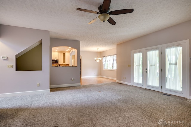unfurnished living room with a chandelier, a textured ceiling, a ceiling fan, carpet floors, and baseboards