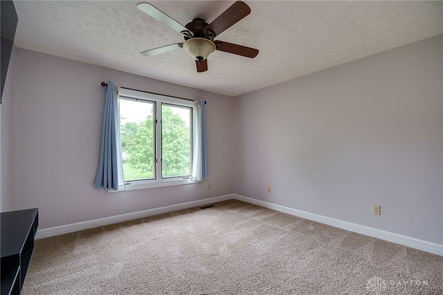 spare room with baseboards, a textured ceiling, carpet floors, and ceiling fan
