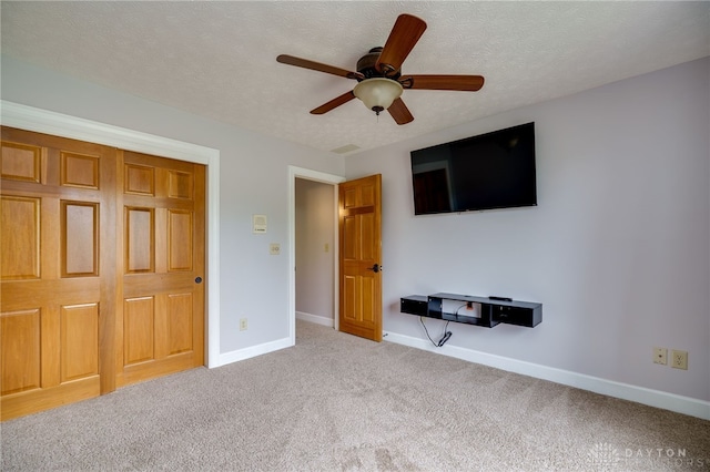 unfurnished bedroom featuring carpet floors, baseboards, ceiling fan, and a textured ceiling