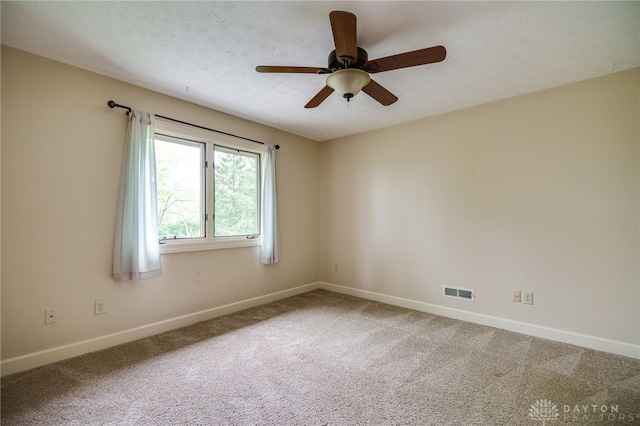 unfurnished room featuring baseboards, light carpet, a ceiling fan, and a textured ceiling