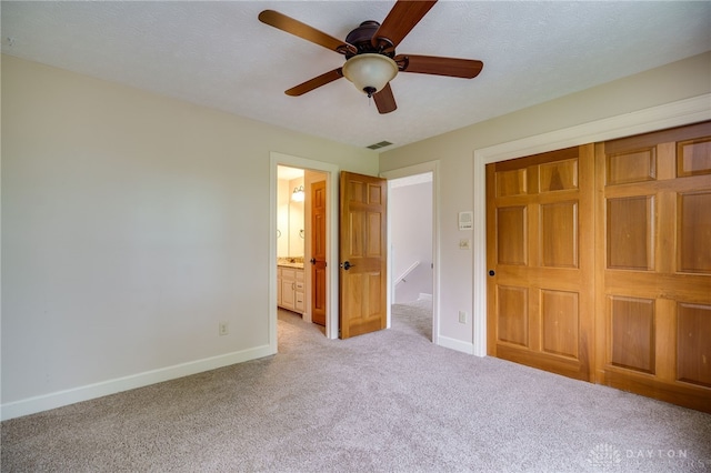 unfurnished bedroom featuring light colored carpet, baseboards, a closet, and connected bathroom