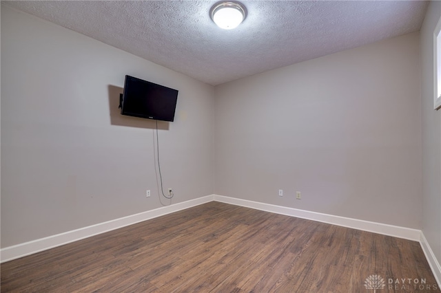 unfurnished room with baseboards, dark wood-type flooring, and a textured ceiling