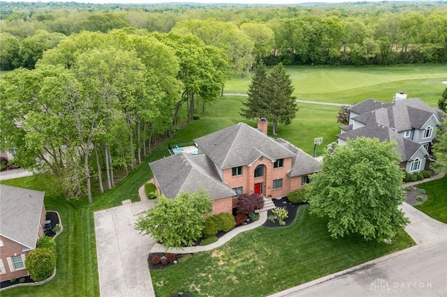 view from above of property with a heavily wooded area and a golf course