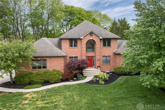 view of front of property featuring roof with shingles, brick siding, and a front yard