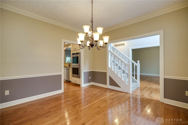 unfurnished dining area with crown molding, a chandelier, stairs, light wood-type flooring, and baseboards