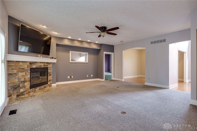 unfurnished living room featuring ceiling fan, carpet flooring, arched walkways, a fireplace, and recessed lighting
