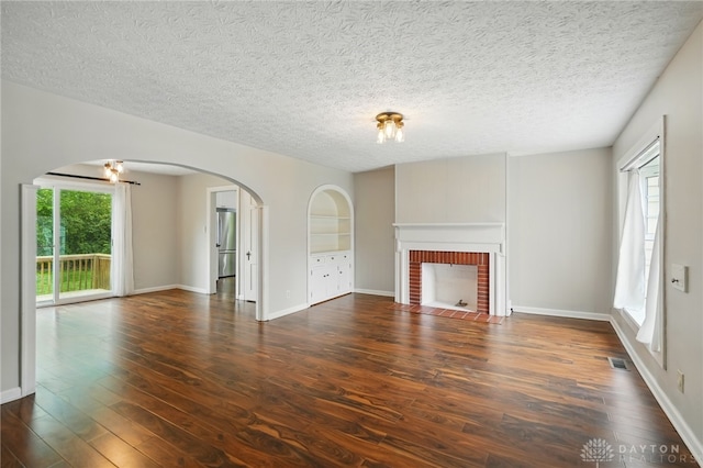2917 California Ave, Dayton, OH 45419 - unfurnished living room featuring arched walkways, wood finished floors, a fireplace, a textured ceiling, and baseboards