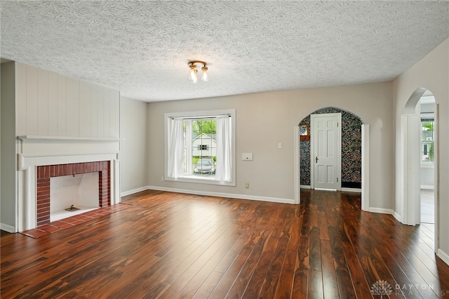 2917 California Ave, Dayton, OH 45419 - unfurnished living room with arched walkways, a fireplace, hardwood / wood-style floors, a textured ceiling, and baseboards