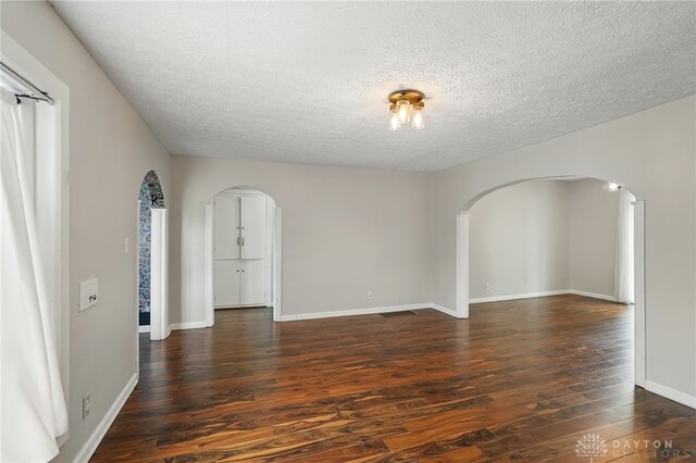 2917 California Ave, Dayton, OH 45419 - unfurnished room featuring arched walkways, dark wood finished floors, a textured ceiling, and baseboards