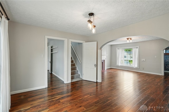 2917 California Ave, Dayton, OH 45419 - spare room with arched walkways, a textured ceiling, dark wood-style flooring, baseboards, and stairs