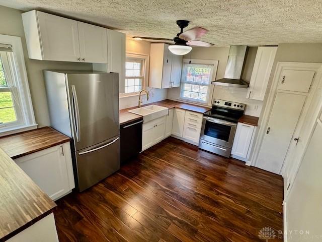 2917 California Ave, Dayton, OH 45419 - kitchen with wall chimney range hood, appliances with stainless steel finishes, a sink, dark wood-style floors, and white cabinets