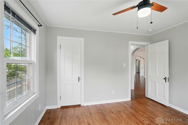 2917 California Ave, Dayton, OH 45419 - unfurnished bedroom featuring arched walkways, multiple windows, wood finished floors, and baseboards