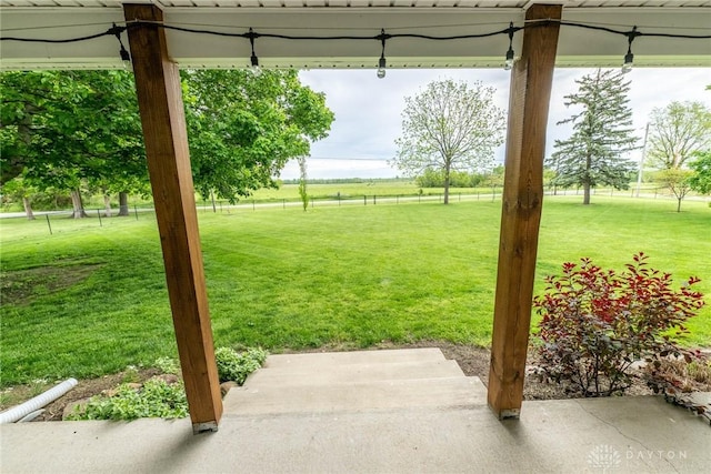 view of green lawn with a rural view and a patio area