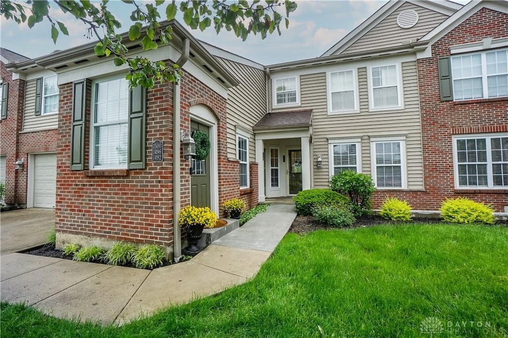 1492 Shadowood Trl, Maineville, OH 45039 - townhome / multi-family property featuring brick siding, a front yard, an attached garage, and driveway