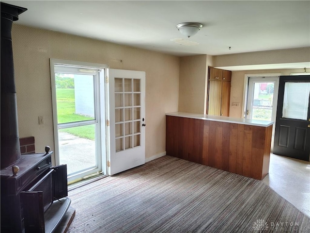 465 W Staunton Rd, Troy, OH 45373 - kitchen featuring a wood stove, brown cabinetry, a peninsula, light countertops, and light carpet