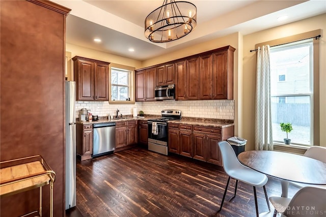 320 N Mechanic St, Lebanon, OH 45036 - kitchen with appliances with stainless steel finishes, dark wood-style flooring, a chandelier, decorative backsplash, and dark countertops