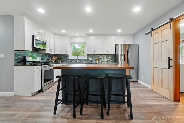 56 W Xenia St, Jamestown Vlg, OH 45335 - kitchen featuring appliances with stainless steel finishes, a barn door, a kitchen bar, white cabinets, and recessed lighting
