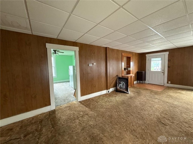 318 E Main St, Bradford, OH 45308 - unfurnished living room featuring carpet flooring, a drop ceiling, wood walls, and baseboards