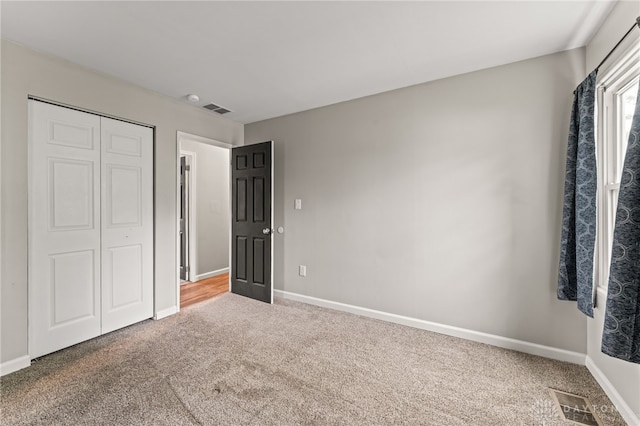unfurnished bedroom featuring carpet floors, baseboards, and a closet