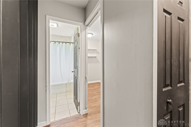 corridor with light wood-style flooring and baseboards