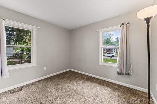 carpeted spare room with plenty of natural light and baseboards