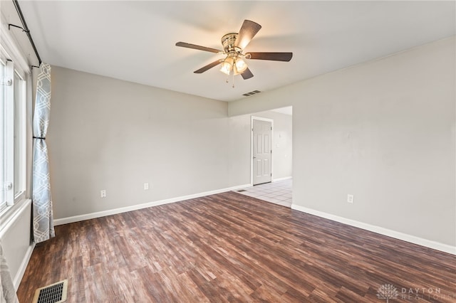 empty room featuring wood finished floors, a ceiling fan, and baseboards