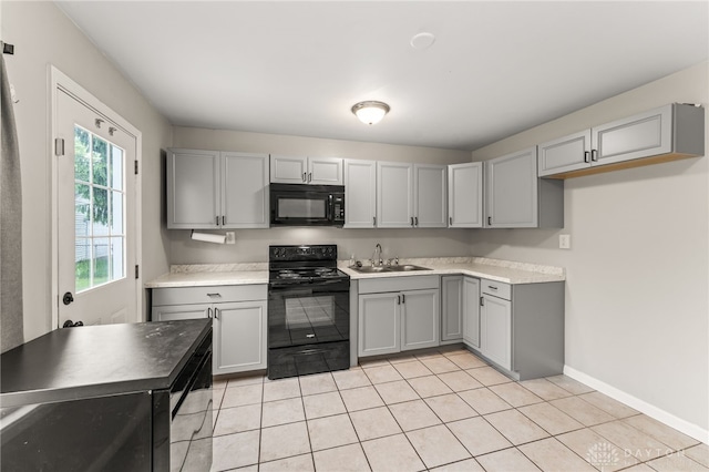 kitchen featuring black appliances, gray cabinets, a sink, light tile patterned floors, and light countertops