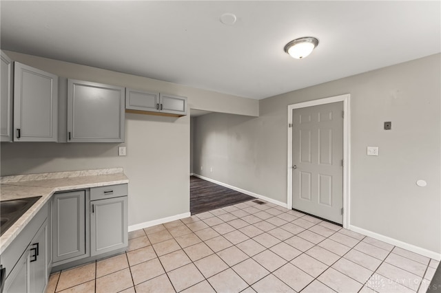 kitchen with gray cabinetry, light countertops, baseboards, and light tile patterned floors