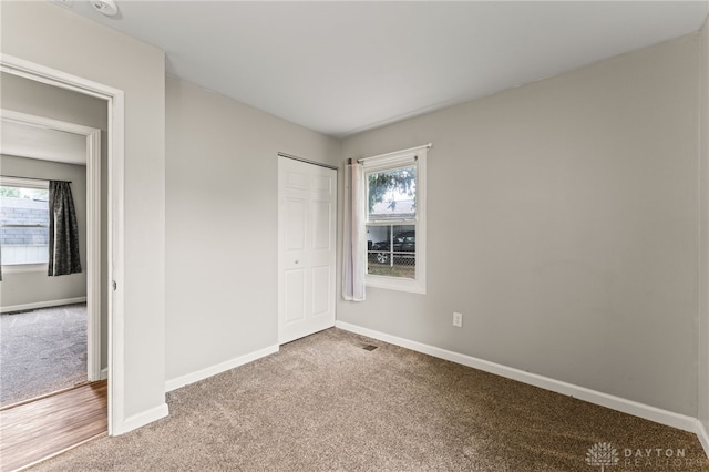 unfurnished bedroom featuring carpet, baseboards, and a closet