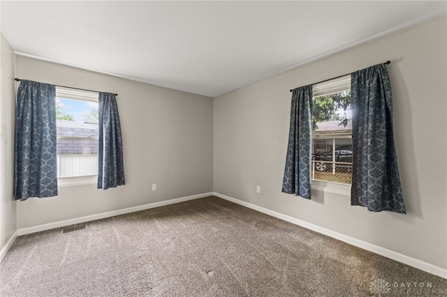 carpeted spare room with plenty of natural light and baseboards
