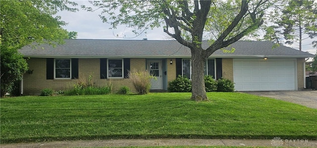 ranch-style home with a garage, concrete driveway, a front yard, and brick siding