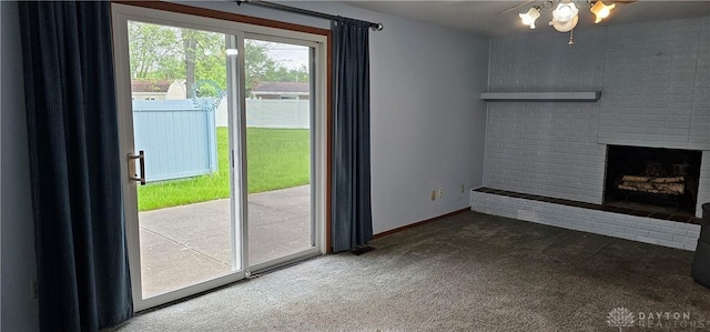 unfurnished living room featuring carpet, a brick fireplace, a ceiling fan, and baseboards