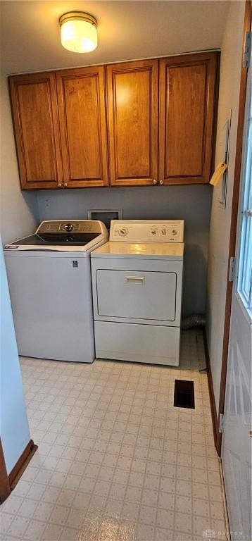 washroom featuring washer and dryer, cabinet space, baseboards, and light flooring