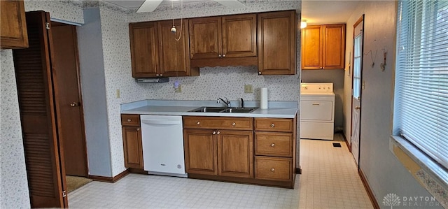 kitchen with a sink, washer / dryer, dishwasher, wallpapered walls, and baseboards