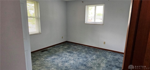 empty room featuring dark carpet and baseboards