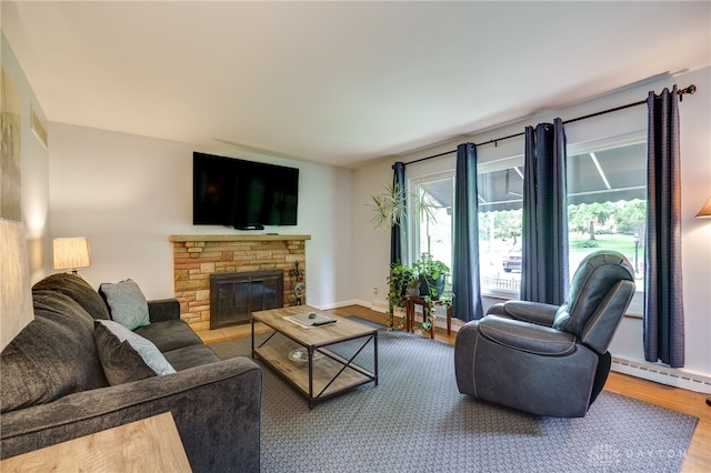 8188 Inwood Ave, Dayton, OH 45415 - living area featuring wood finished floors, a stone fireplace, a baseboard radiator, and baseboards