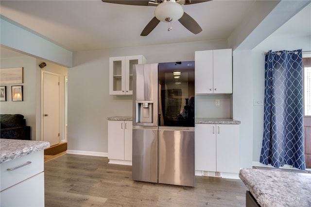8188 Inwood Ave, Dayton, OH 45415 - kitchen with stainless steel fridge with ice dispenser, a ceiling fan, light wood-style floors, white cabinets, and glass insert cabinets