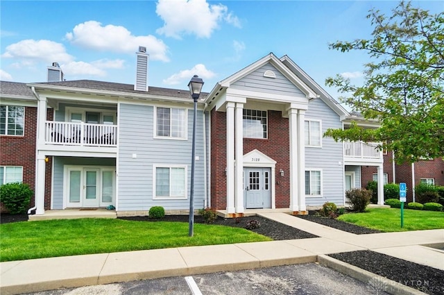 3128 Alexander Pl Unit 206, Beavercreek, OH 45431 - view of front of home with uncovered parking, a front lawn, a chimney, and a balcony