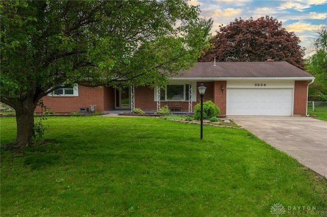view of front of home featuring concrete driveway, a garage, a front yard, covered porch, and brick siding