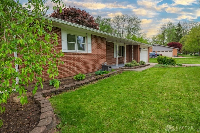 ranch-style house featuring brick siding, a front lawn, a garage, and central air condition unit